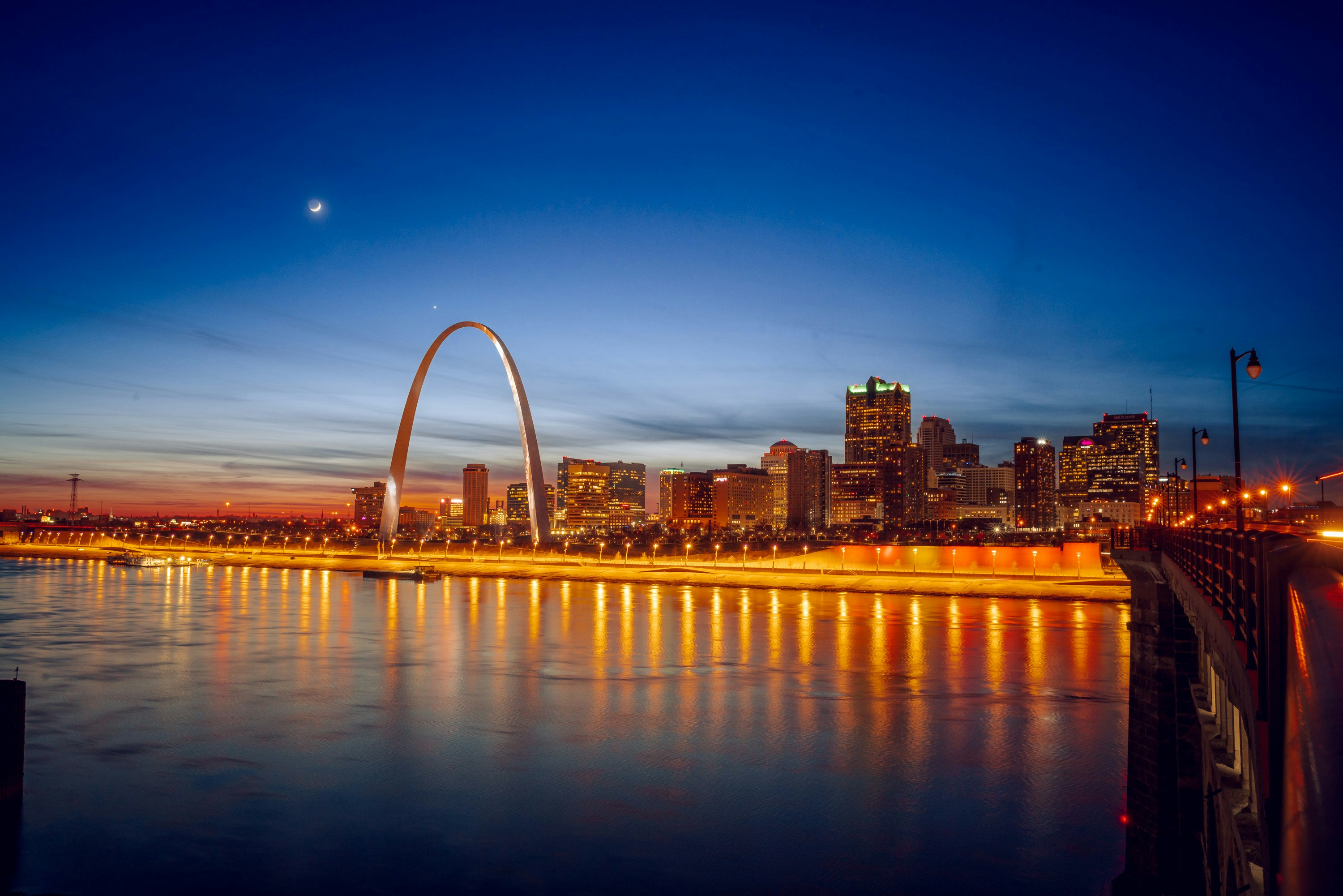 The Gateway Arch and downtown St. Louis skyline at dusk, reflected in the Mississippi River